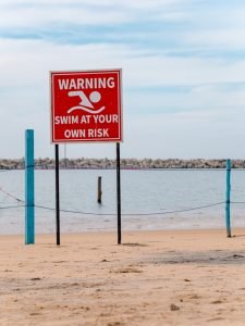 Un panneau d'avertissement sur une plage à côté d'un plan d'eau