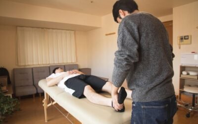 Homme allongé sur table de massage, autre homme manipulant son pied dans une pièce