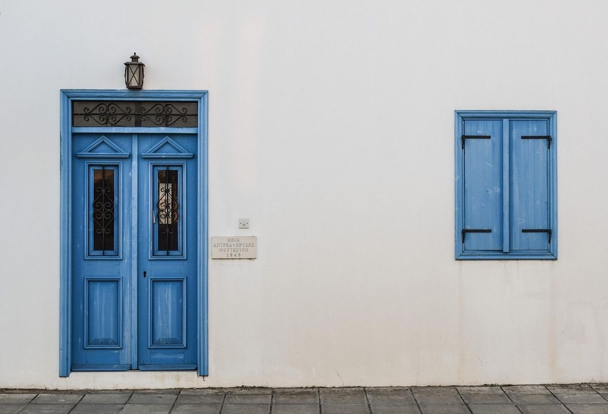 Porte et fenêtre bleues sur mur blanc avec lampe et pavés Porte et fenêtre bleues sur mur blanc avec lampe et pavés