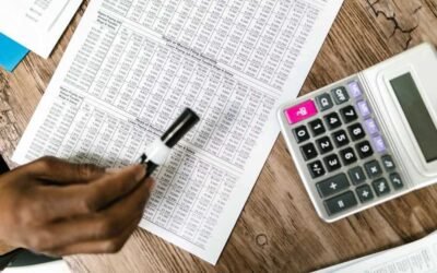 Une main écrit sur un tableau de chiffres avec une calculatrice