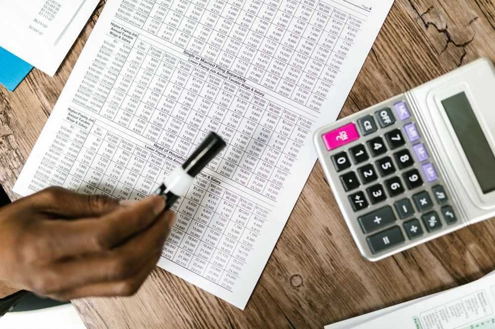 Une main écrit sur un tableau de chiffres avec une calculatrice