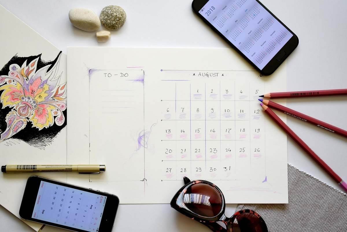 Planification d'août sur papier avec smartphone, crayons et accessoires Planification d'août sur papier avec smartphone, crayons et accessoires