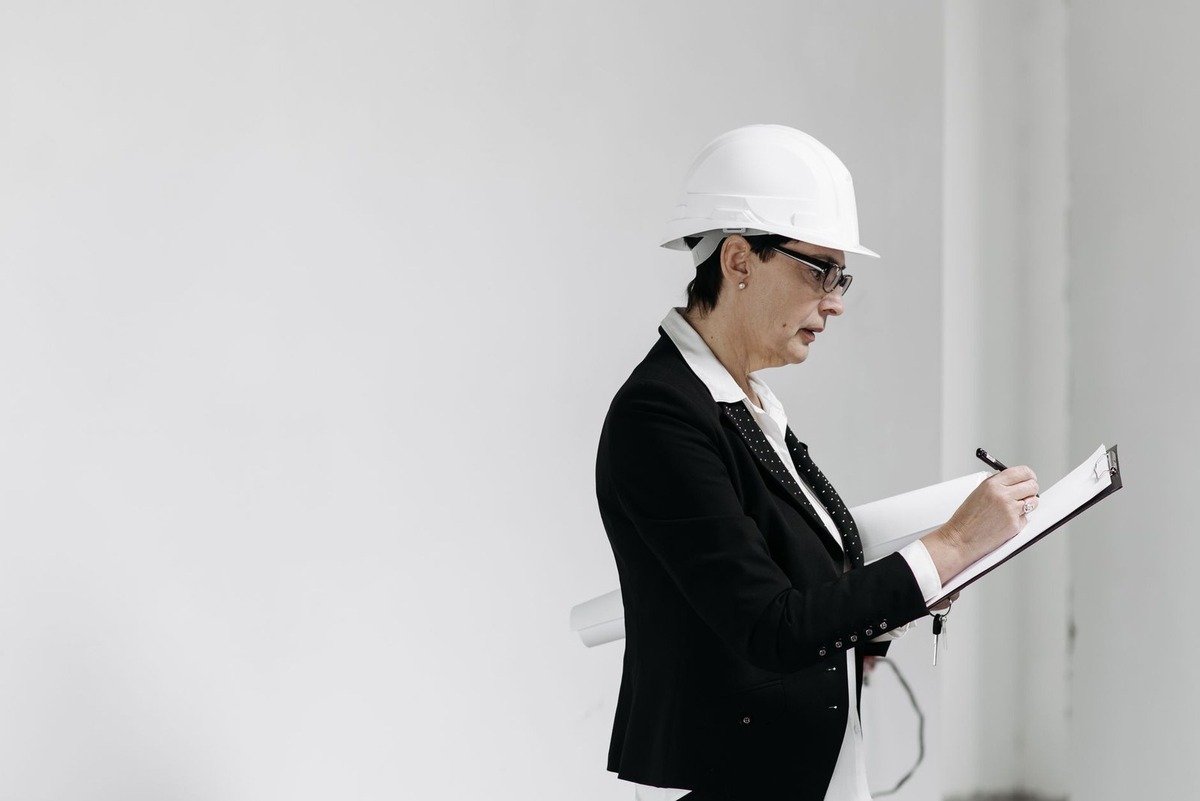 Professionnelle en tenue de chantier prenant des notes sur un tableau Professionnelle en tenue de chantier prenant des notes sur un tableau
